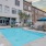 a pool with chairs and umbrellas by a building