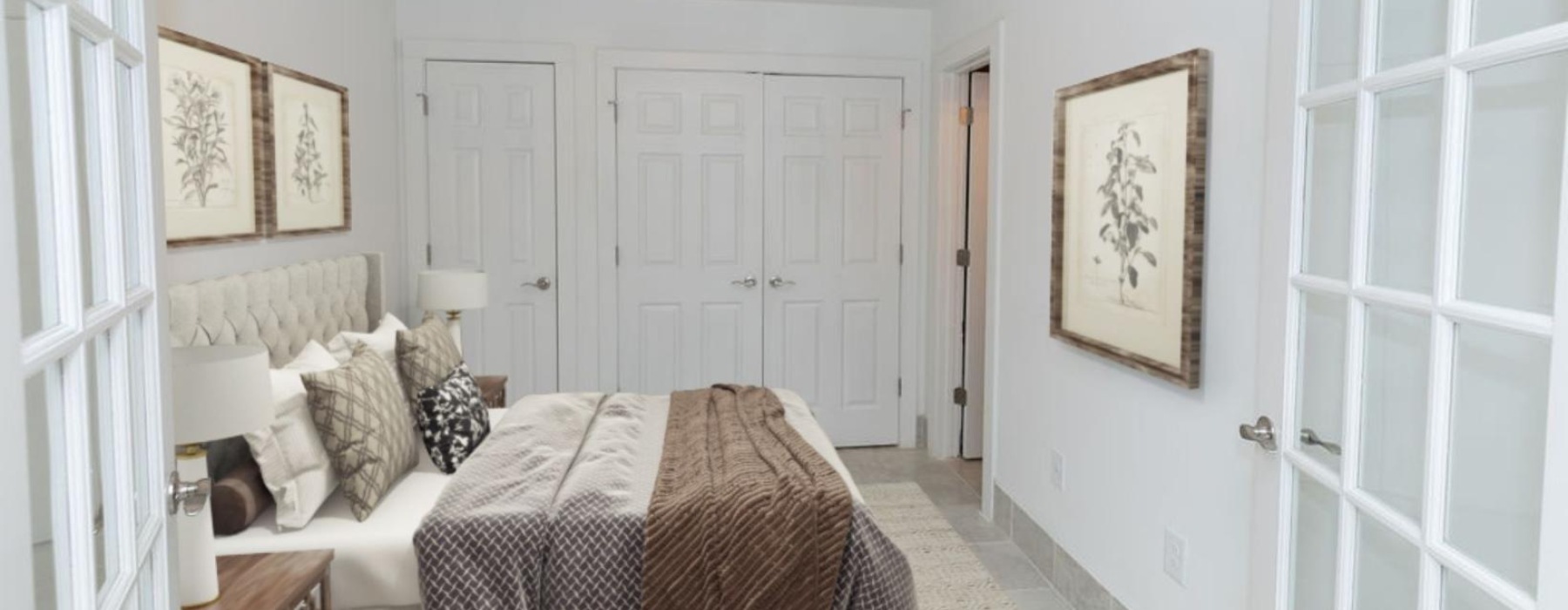 Elegantly styled bedroom with white walls, double closets, bedside lamps, and textured throw blankets.